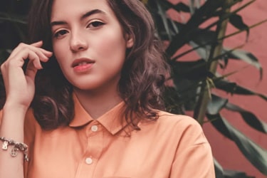 Woman with orange shirt on, posing to the camera.