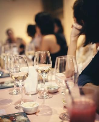 Wine glasses and peaople sitting at the table.