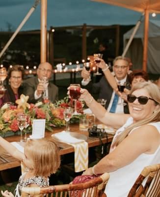 Smiling people rising wine glasses for toast.