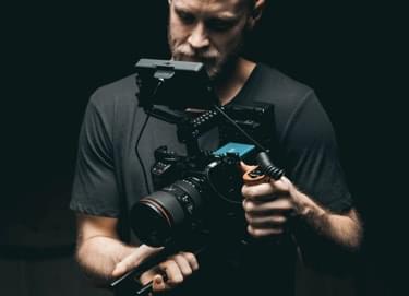 Man on the black background holding a camera.